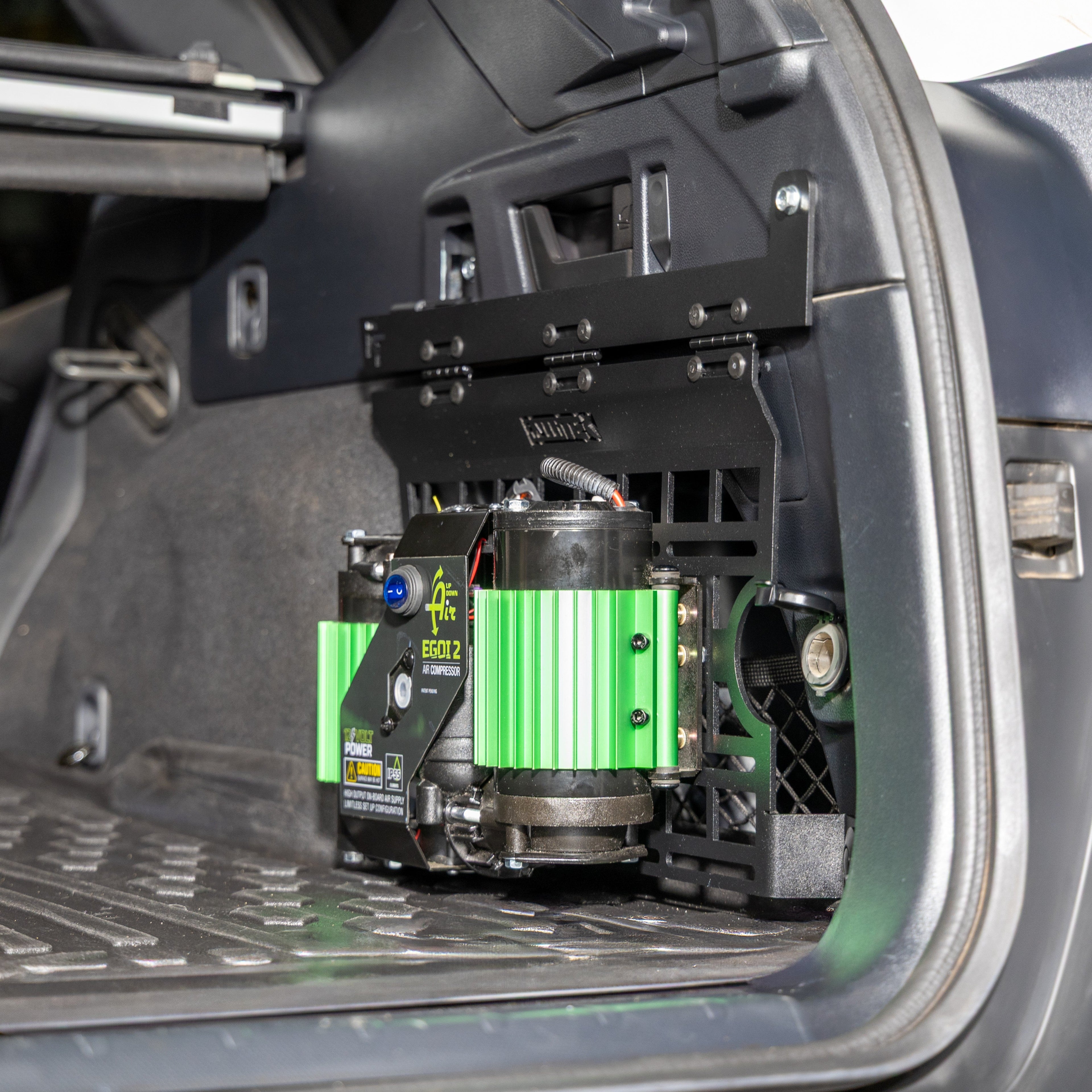 subaru outback molle panel installed in rear cargo storage area with air compressor mounted on it.