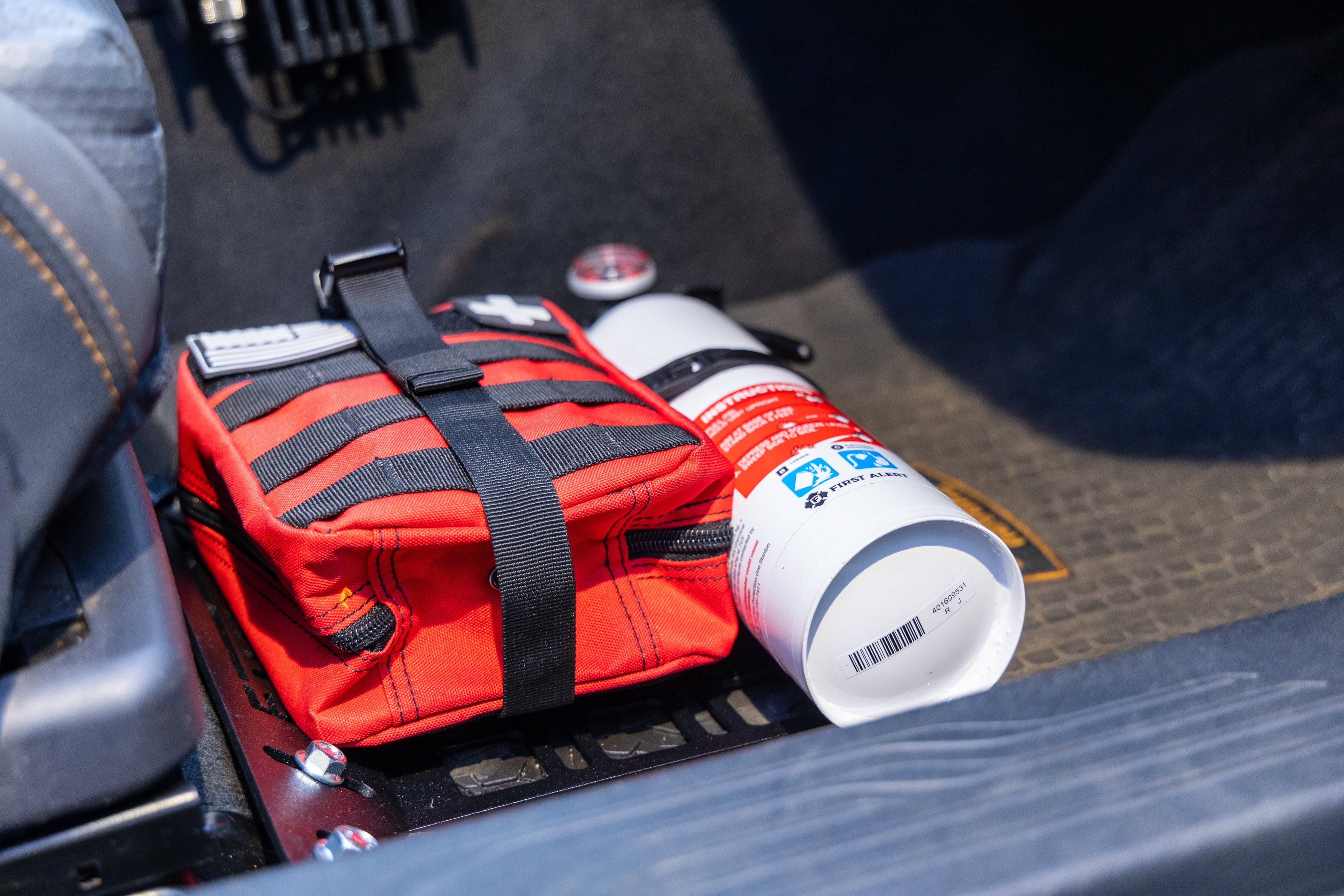 Red molle bag and white fire extinguisher attached to Rallitek seat bracket fire extinguisher mount